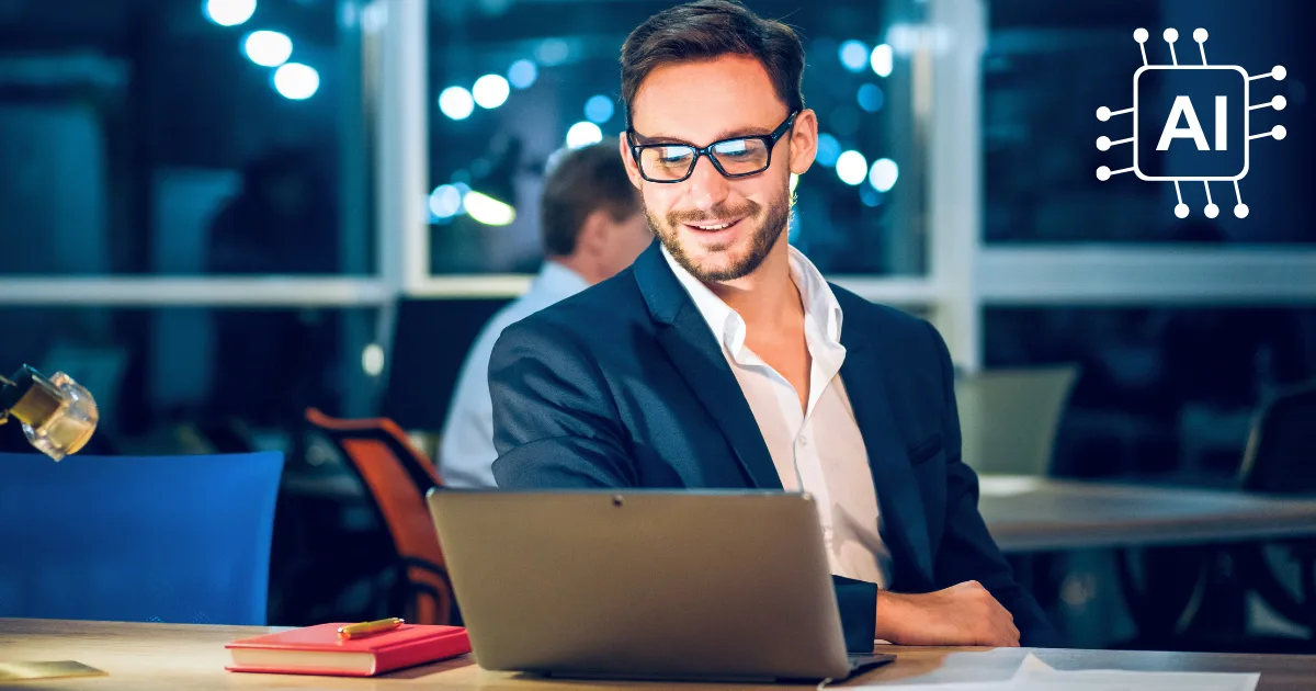 A man in a suit and glasses smiles while working on a laptop at his desk in a modern office. A notebook and pen are nearby, highlighting an AI automation case study with an AI chip icon displayed in the top right corner.