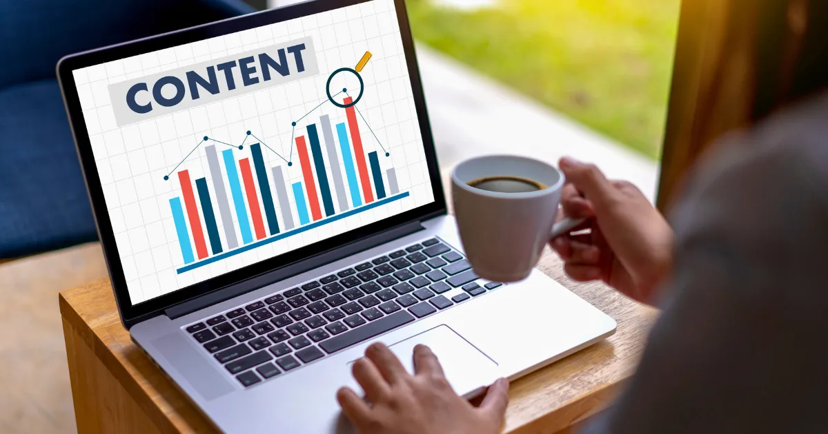 A person holding a cup of coffee looks at a laptop screen displaying a bar graph labeled CONTENT, with a magnifying glass highlighting one bar—illustrating the power of a solid content strategy blueprint.