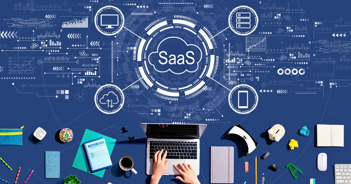 A person types on a laptop surrounded by office supplies, with “no-code SaaS” in the center of a digital cloud and connected icons representing cloud computing, mobile, and software applications on a blue background.