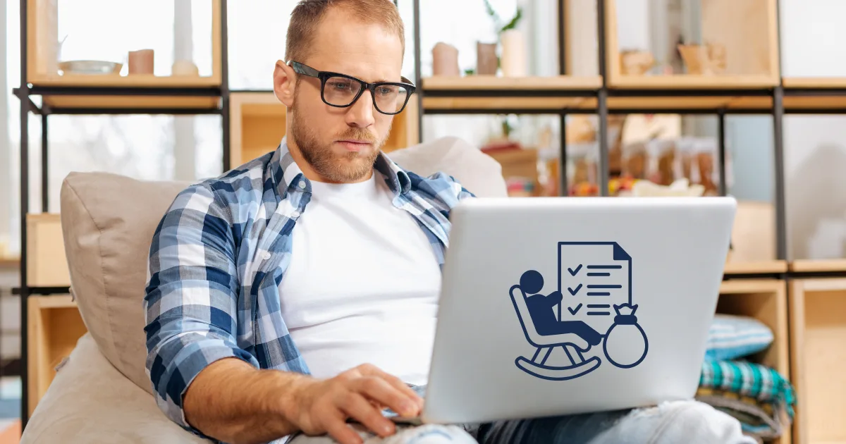 A man wearing glasses and a plaid shirt sits on a couch, focused on his laptop. A sticker on the laptop hints at self-employed retirement with a rocking chair, checklist, and money bag. Shelves and home decor fill the background.