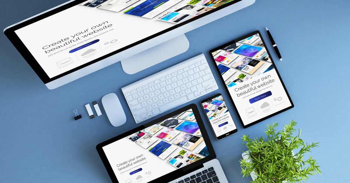 Several digital devices, including a desktop computer, laptop, tablet, and smartphone, display the homepage created with the best website builder. The setup sits on a blue desk with a keyboard, mouse, plant, and office supplies.